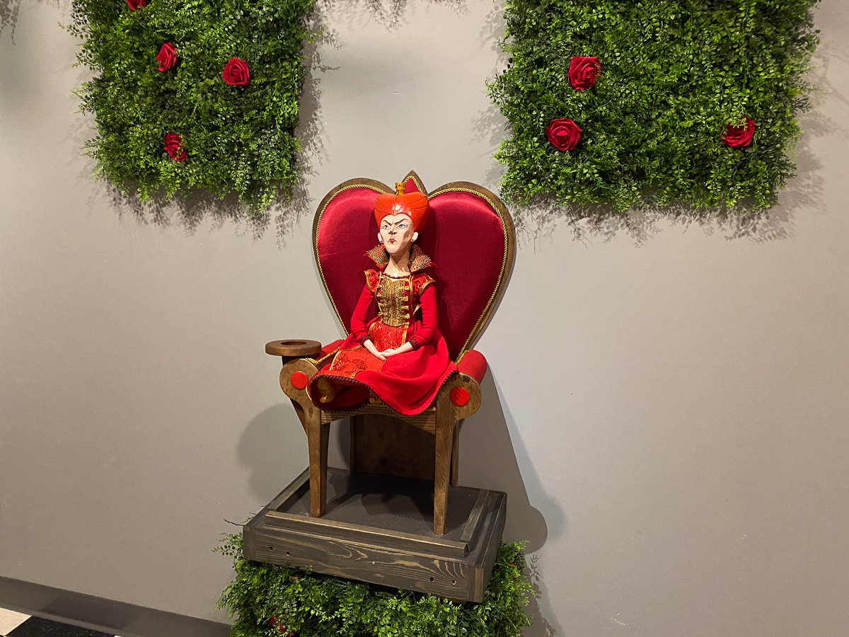 red queen doll in a chair with bushes on both sides